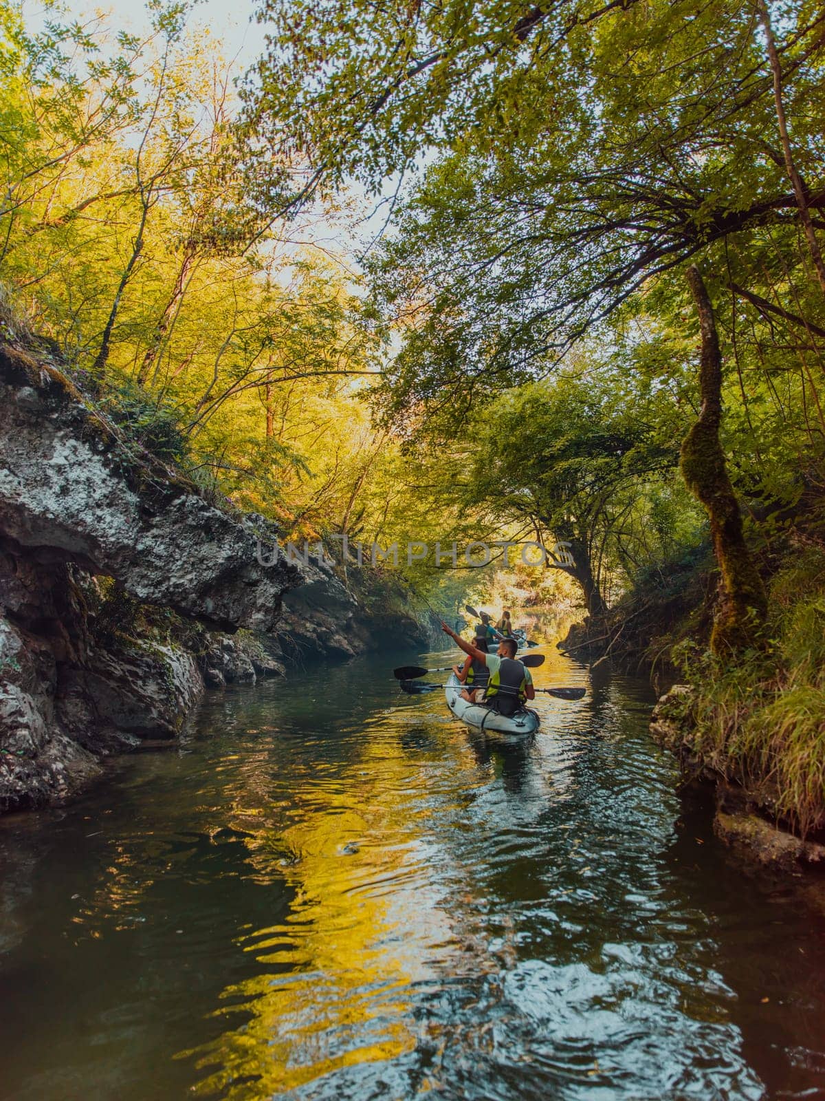 A young couple enjoying an idyllic kayak ride in the middle of a beautiful river surrounded by forest greenery.