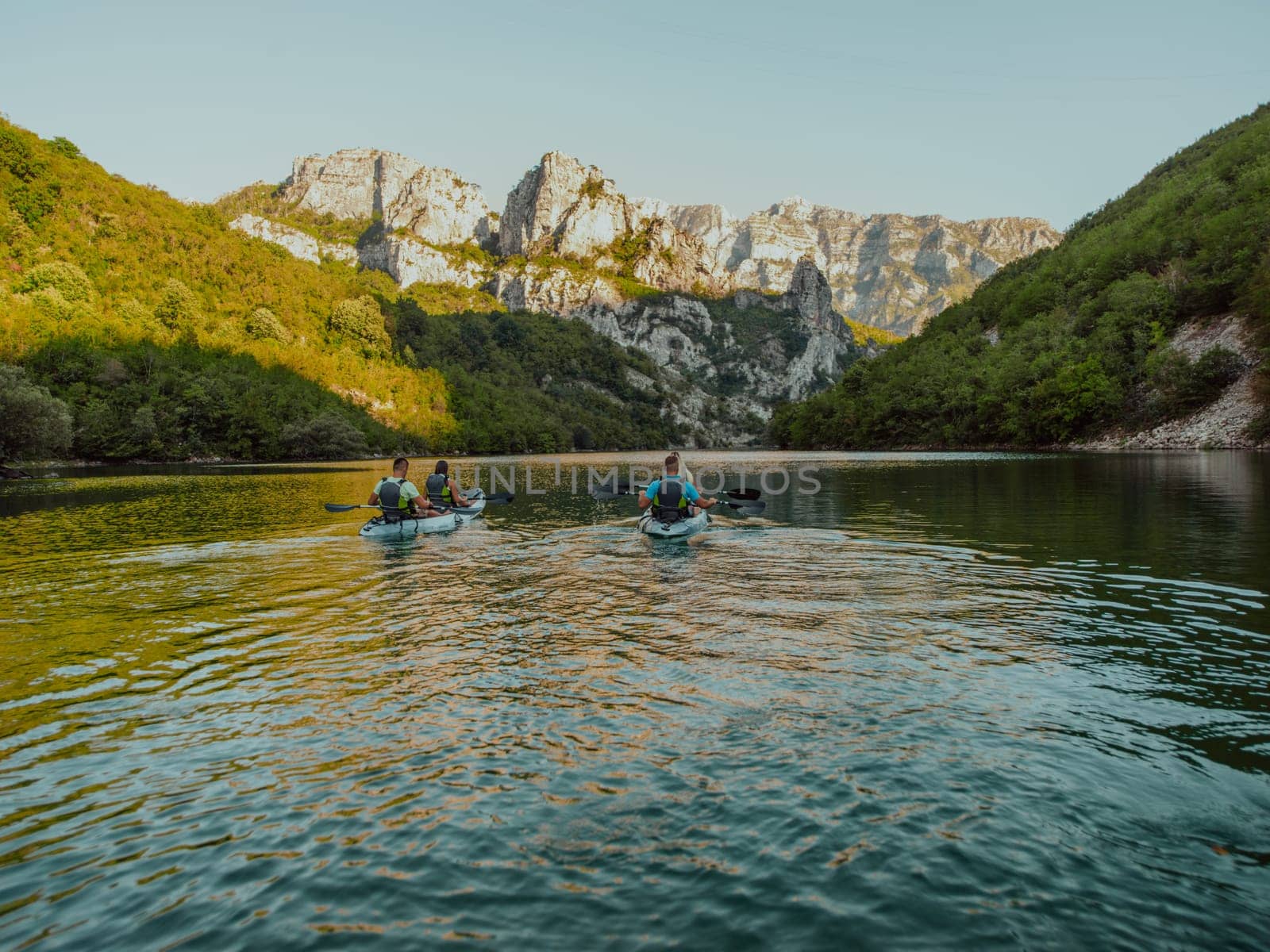 A group of friends enjoying having fun and kayaking while exploring the calm river, surrounding forest and large natural river canyons by dotshock