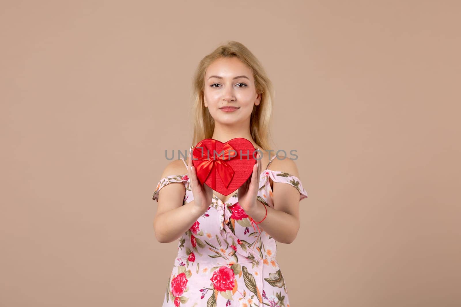 front view young female holding red heart shaped present on brown background feminine sensual money march woman shopping equality horizontal marriage