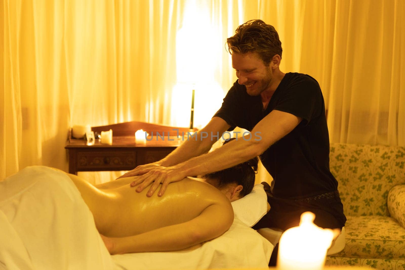 Massage session in SPA salon - smiling man massaging bare back of a woman. Mid shot