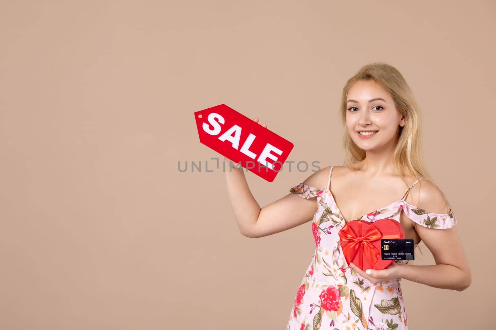 front view young female holding red present sale nameplate and bank card on brown background money march horizontal woman feminine sensual shopping