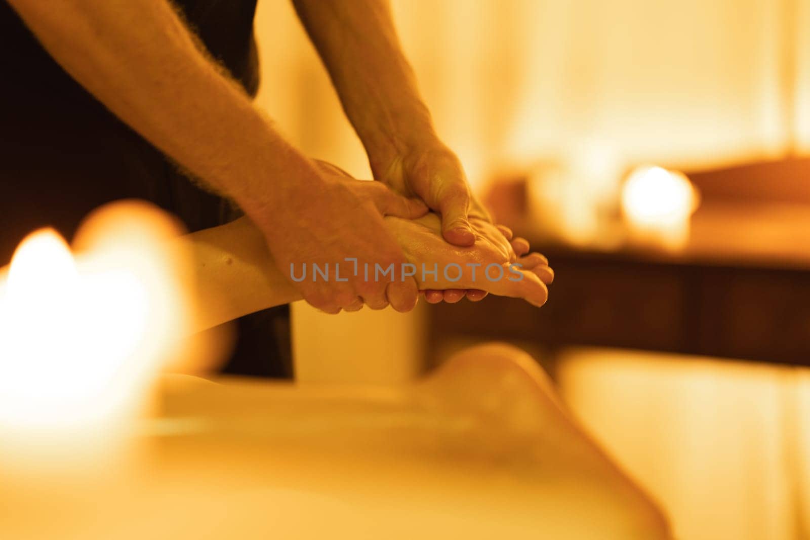 Massage in spa salon - massaging the foot of a woman client. Mid shot