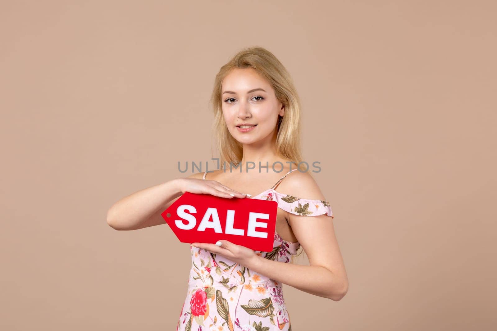 front view young female holding red sale nameplate on brown background money march horizontal sensual shopping woman equality