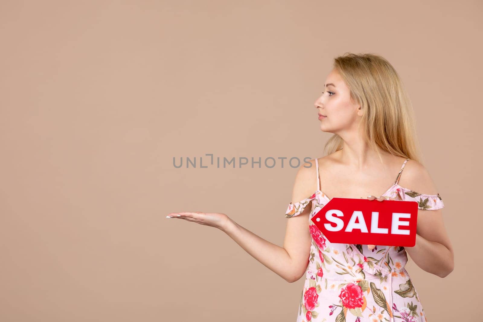 front view young female holding red sale nameplate on brown background money march horizontal sensual shopping woman feminine