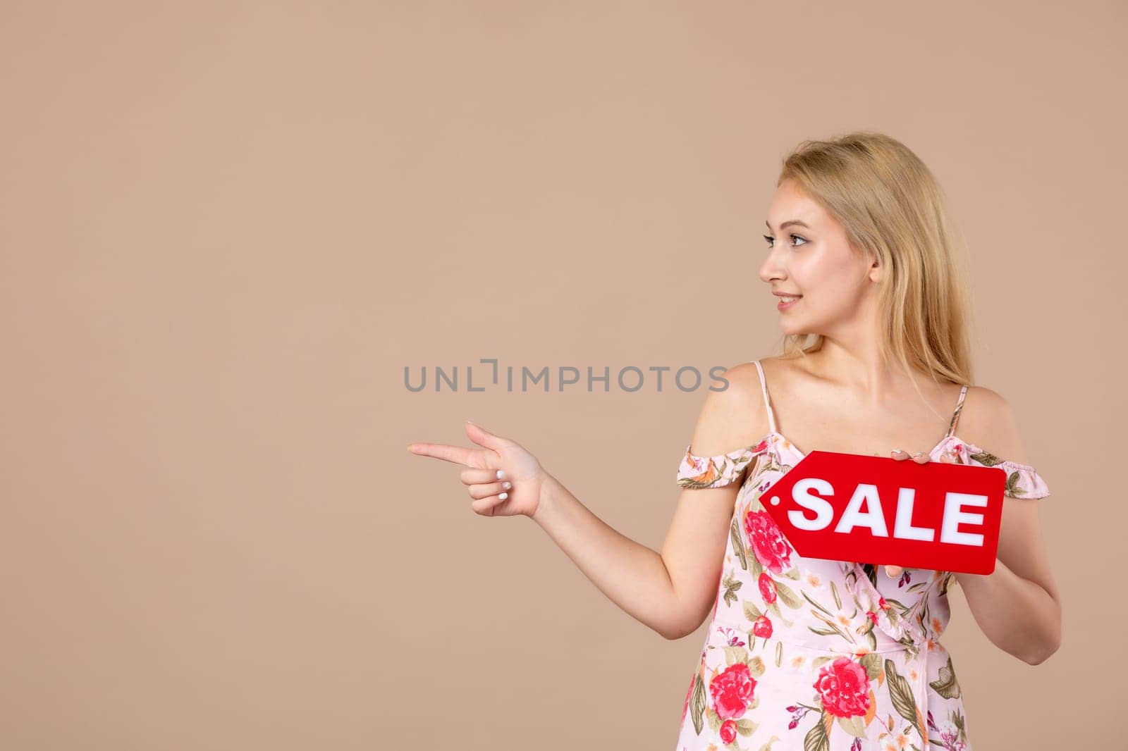 front view young female holding red sale nameplate on brown background money march horizontal sensual woman equality feminine
