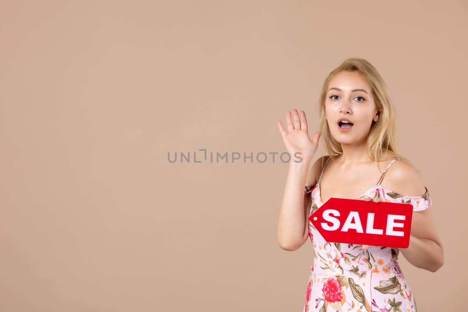 front view young female holding red sale nameplate on brown background woman money march horizontal sensual equality feminine