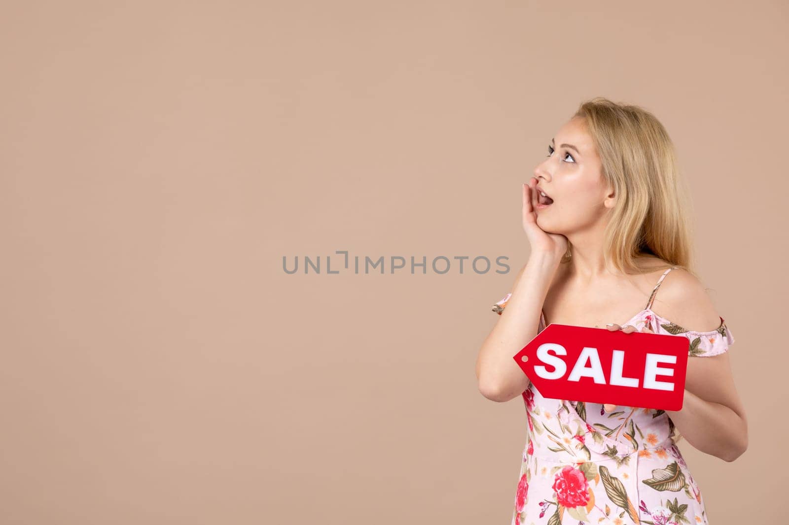 front view young female holding red sale nameplate on brown background woman money march horizontal sensual shopping equality