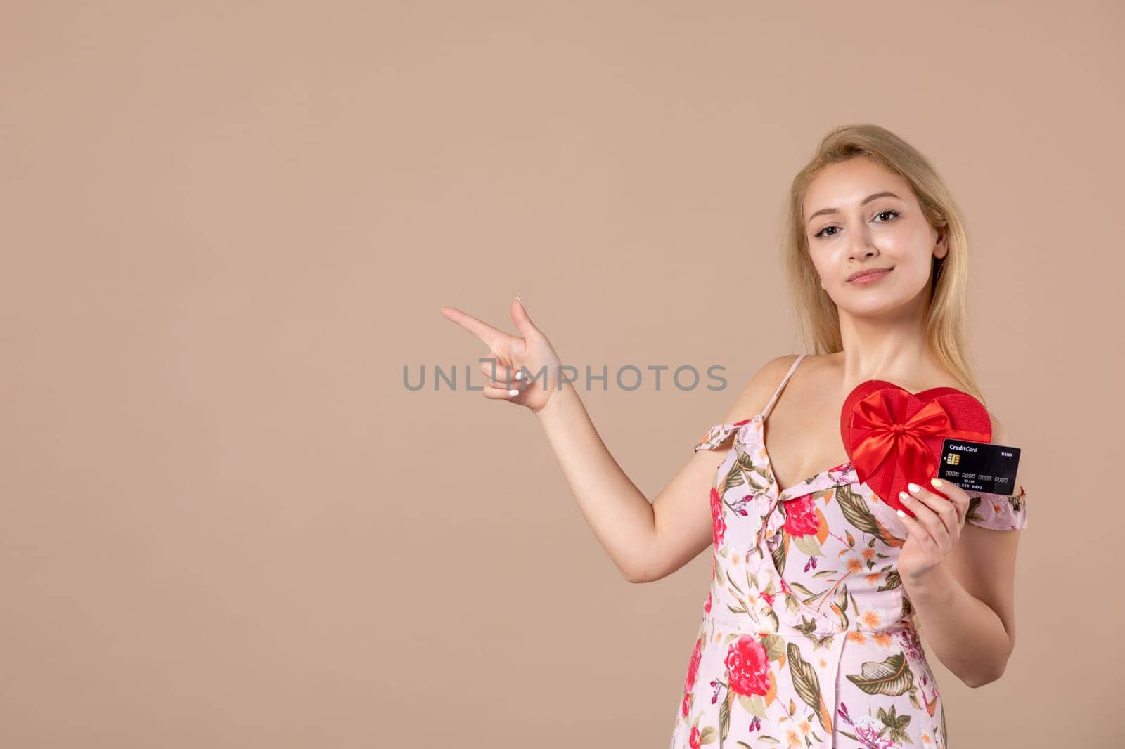 front view young female posing with red heart shaped present and bank card on brown background feminine march sensual horizontal woman money