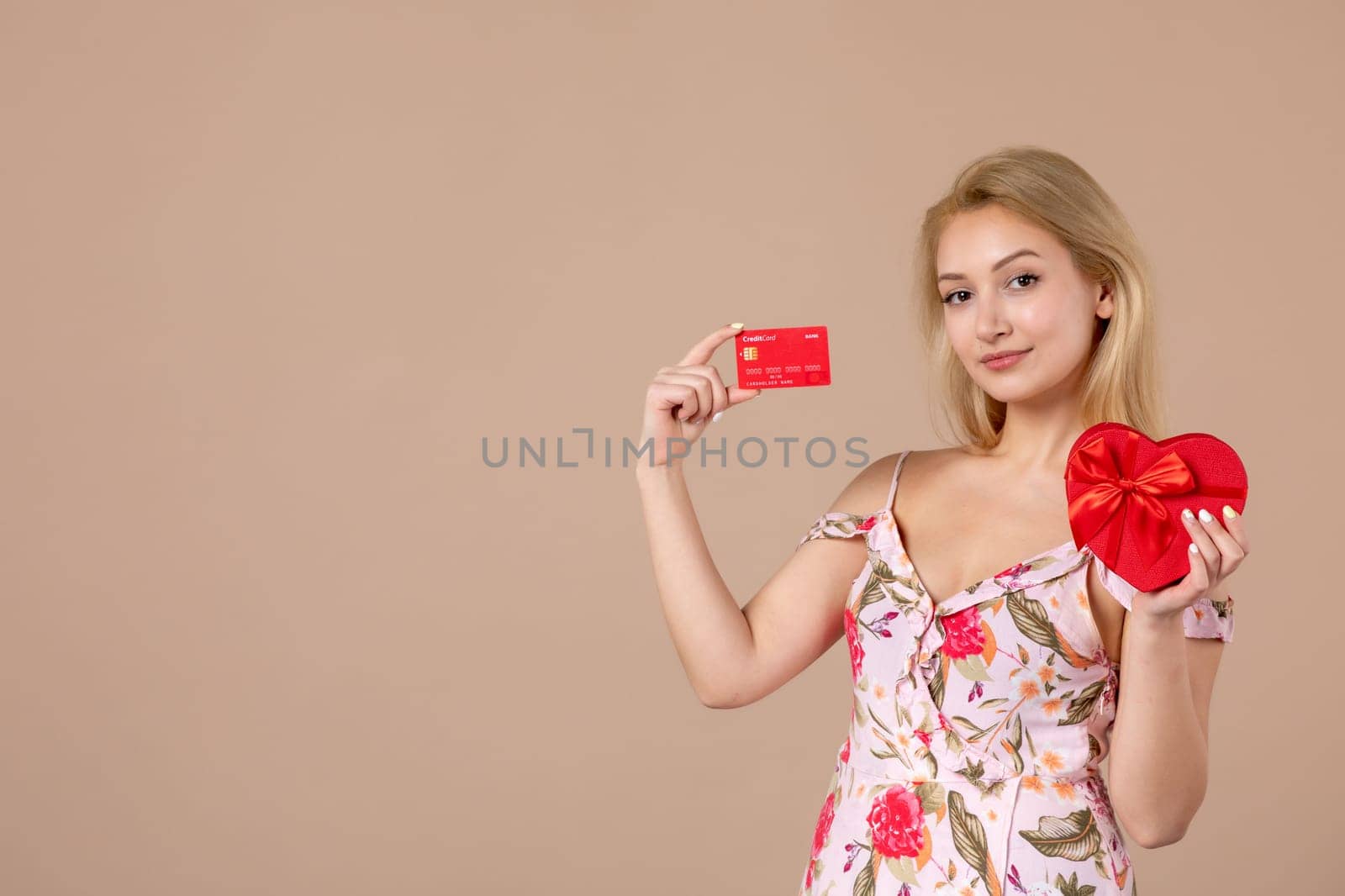 front view young female posing with red heart shaped present and bank card on brown background feminine money march equality woman sensual