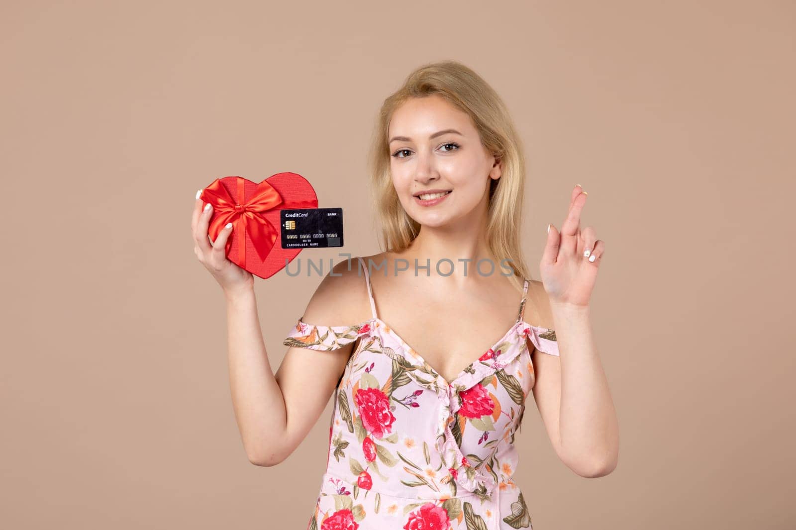 front view young female posing with red heart shaped present and bank card on brown background feminine money march equality woman sensual by Kamran
