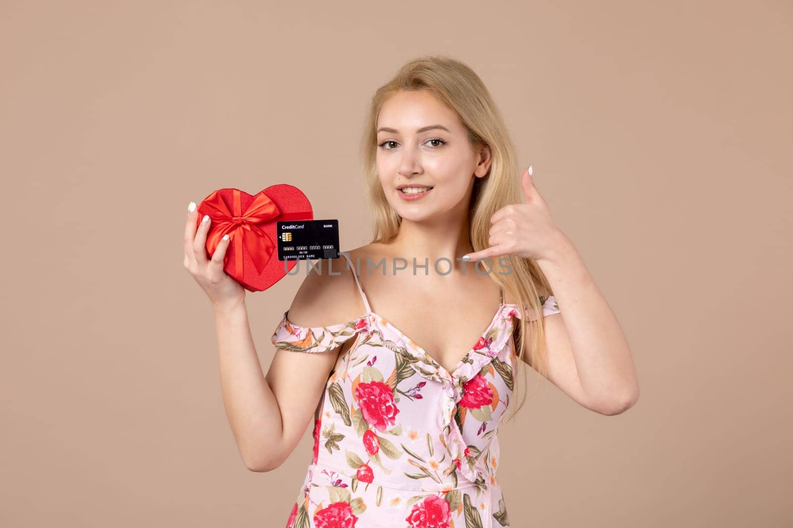front view young female posing with red heart shaped present and bank card on brown background feminine money march woman horizontal equality