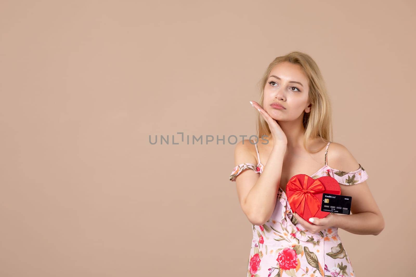 front view young female posing with red heart shaped present and bank card on brown background money march horizontal woman equality sensual