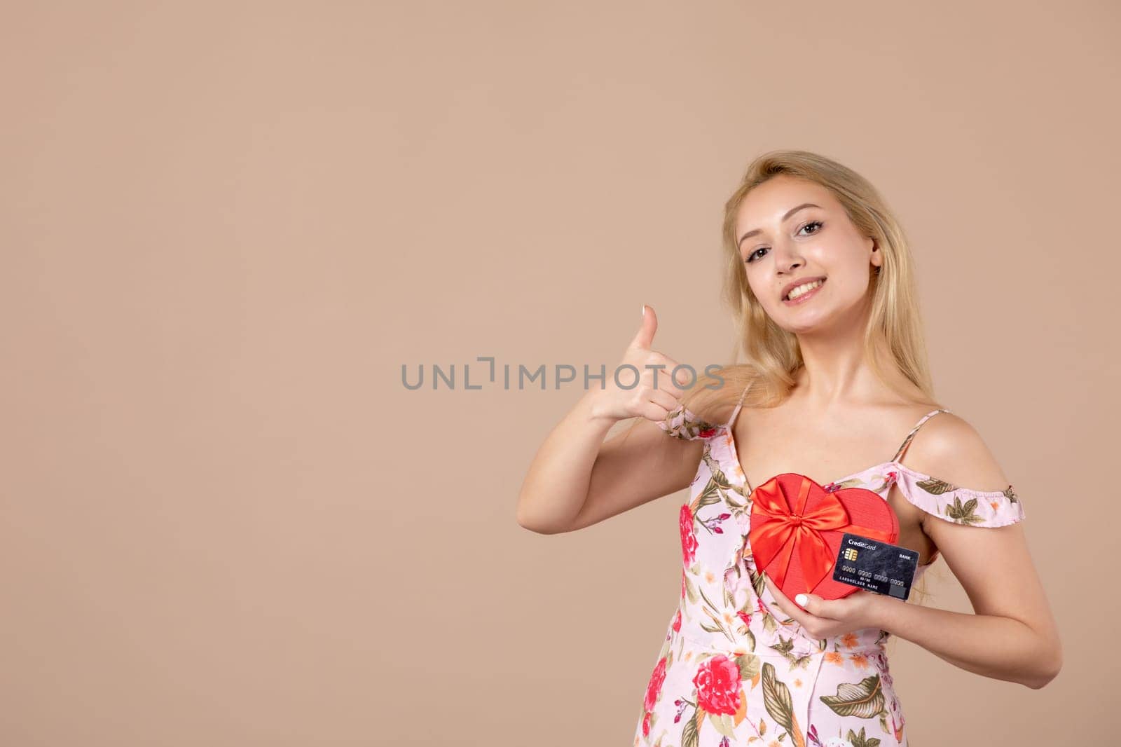 front view young female posing with red heart shaped present and bank card on brown background money march horizontal woman feminine sensual