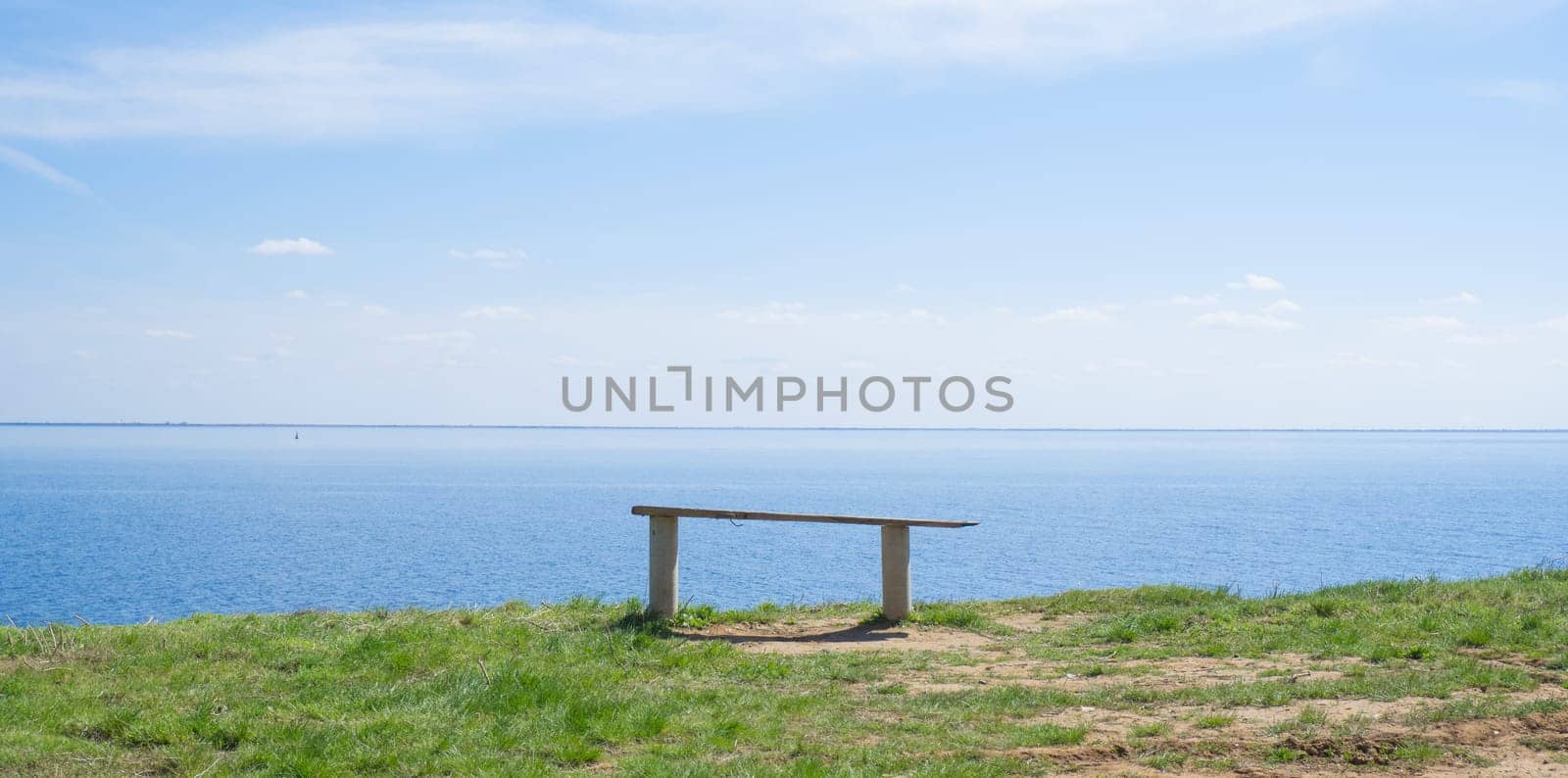 Wooden bench on the shore of the blue sea, lake on a summer sunny day