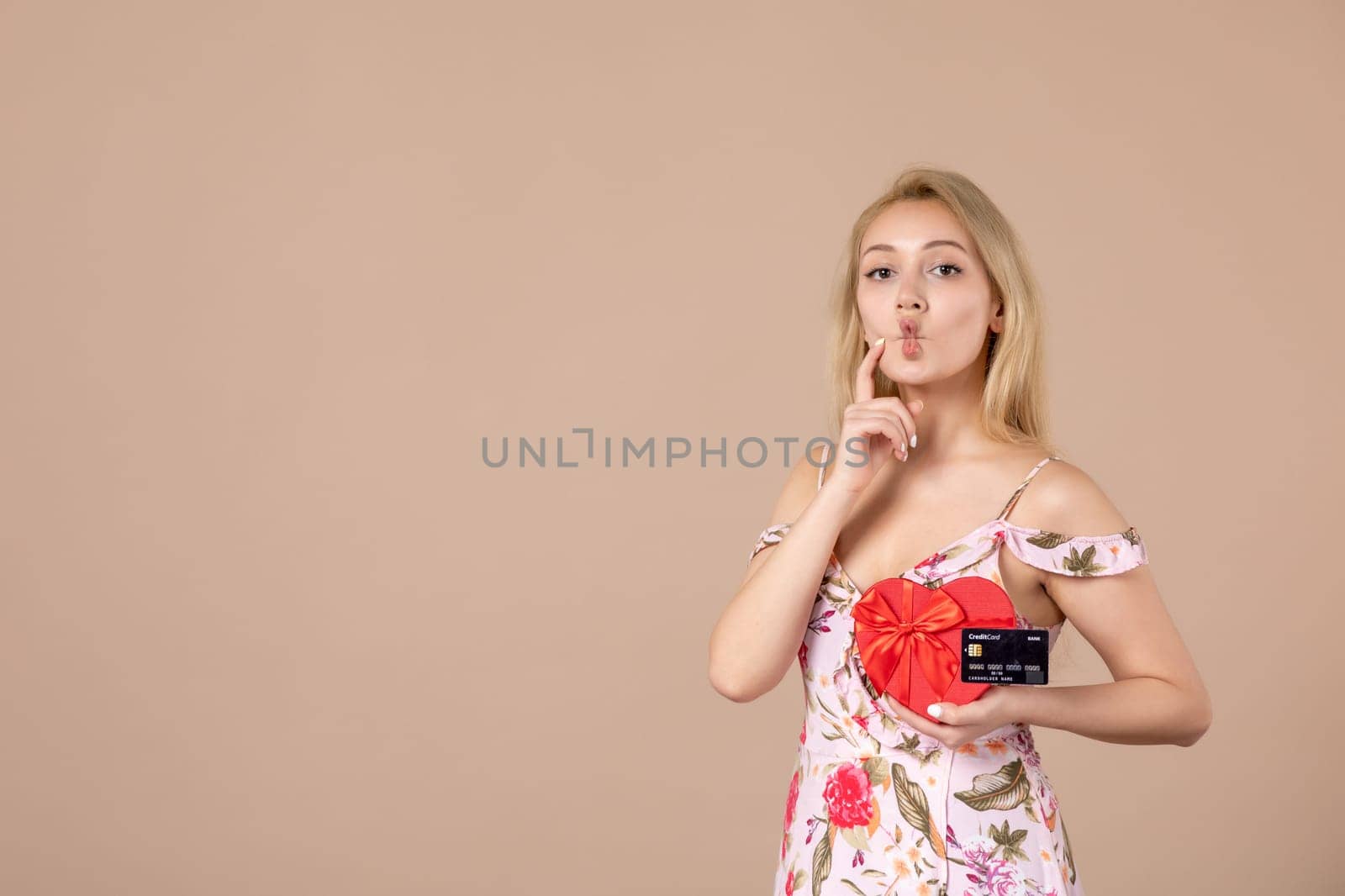 front view young female posing with red heart shaped present and bank card on brown background money equality sensual march woman feminine