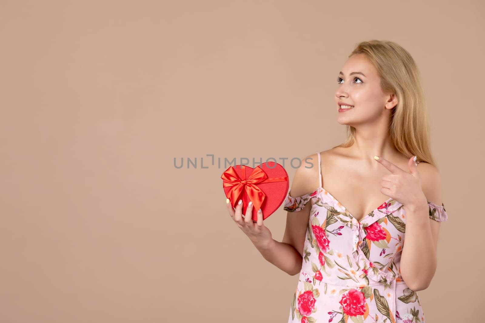front view young female posing with red heart shaped present on brown background marriage feminine shopping money march horizontal equality woman by Kamran