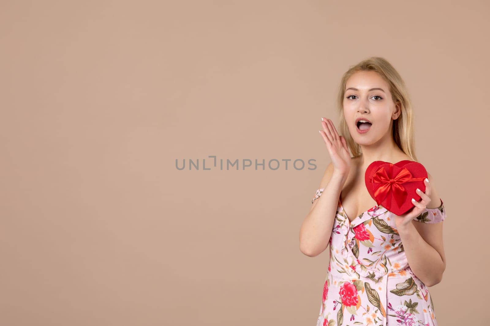 front view young female posing with red heart shaped present on brown background marriage feminine shopping money march horizontal woman sensual by Kamran