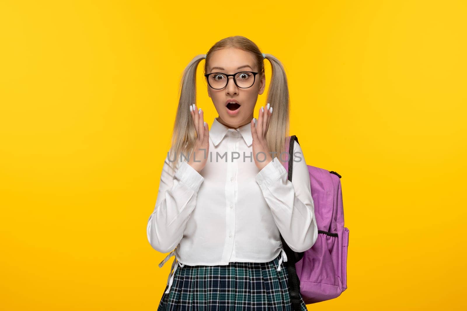 world book day blonde girl with ponytails excited in uniform on yellow background