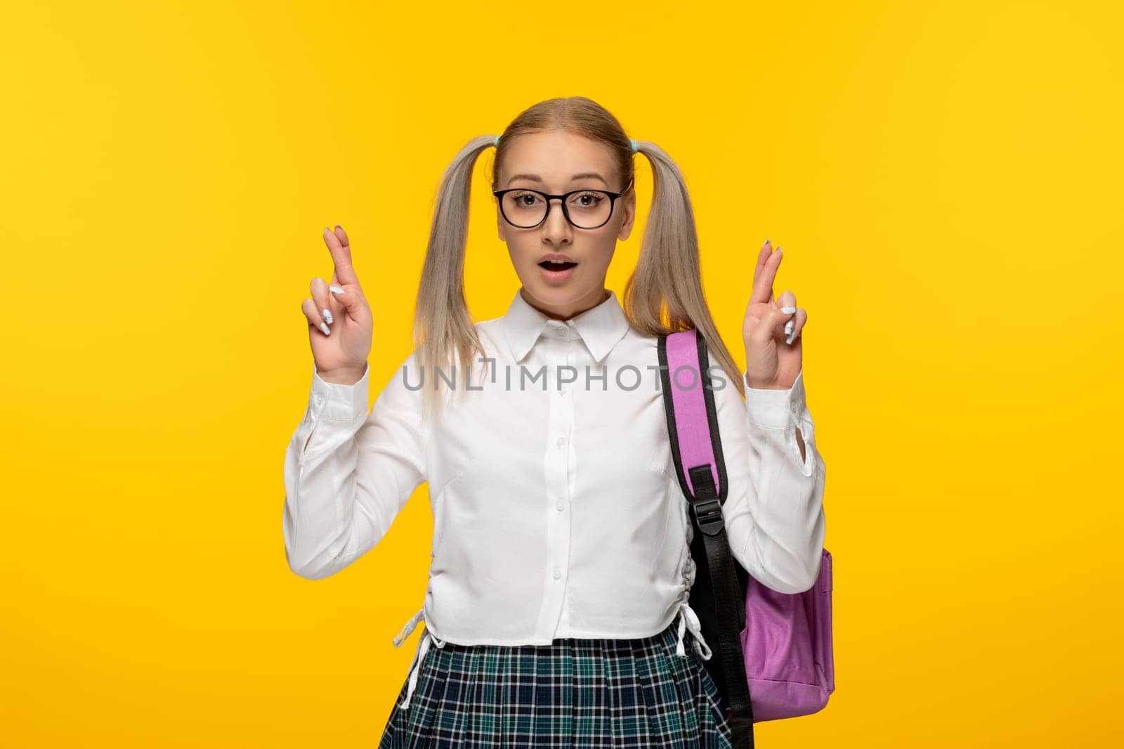 world book day schoolgirl with crossed fingers on yellow background with pink backpack by Kamran