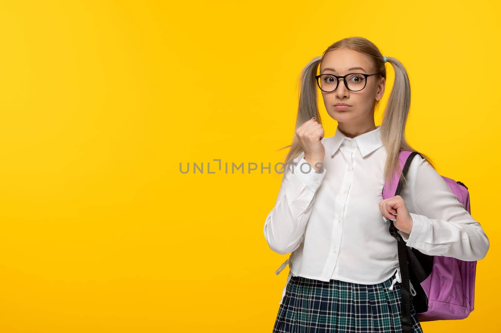 world book day blonde girl in glasses with pink backpack on yellow background