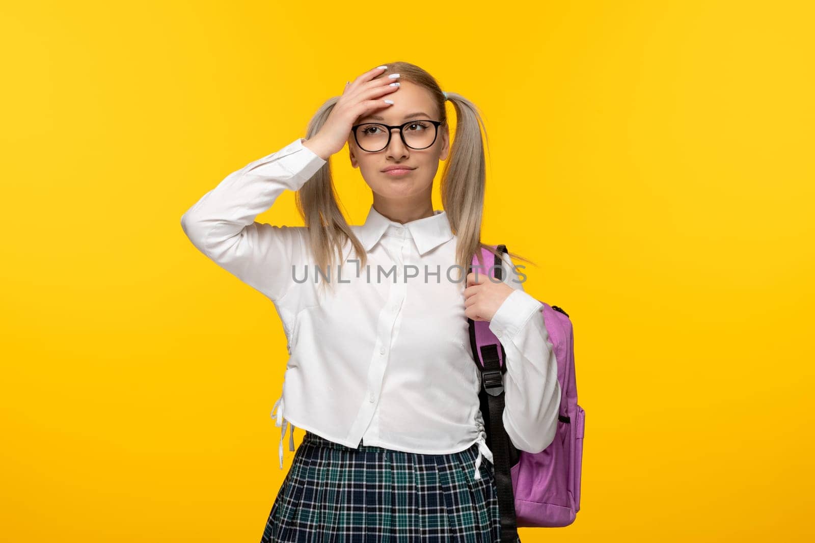 world book day blonde girl touching forehead with backpack on yellow background