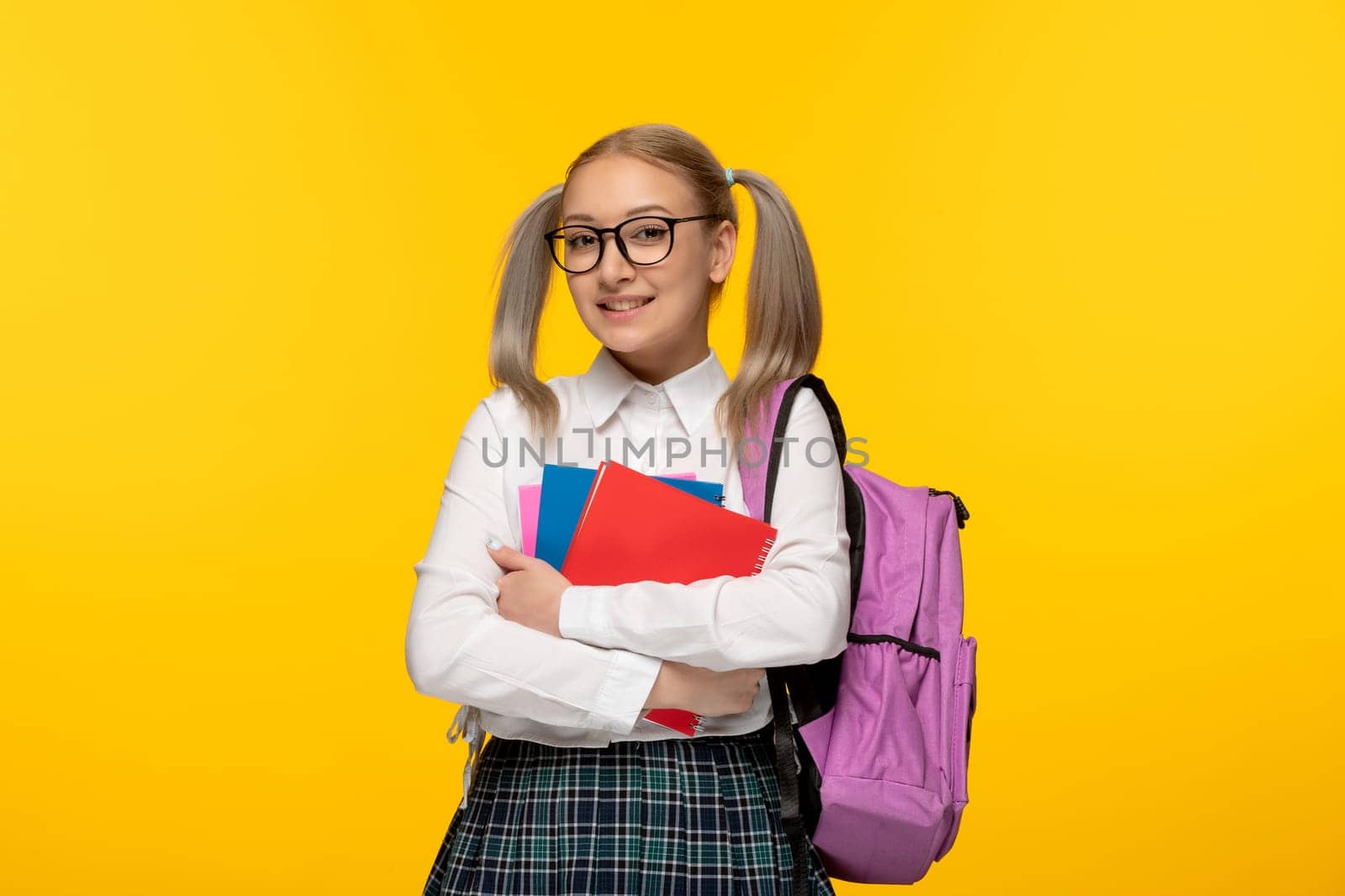 world book day blonde school girl is holding colorful notebooks on yellow background by Kamran