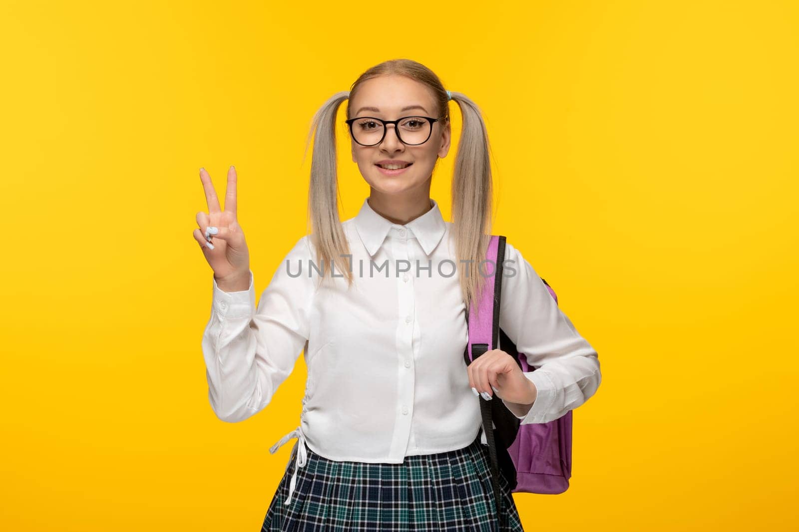 world book day blonde school girl showing peace gesture smiling with backpack