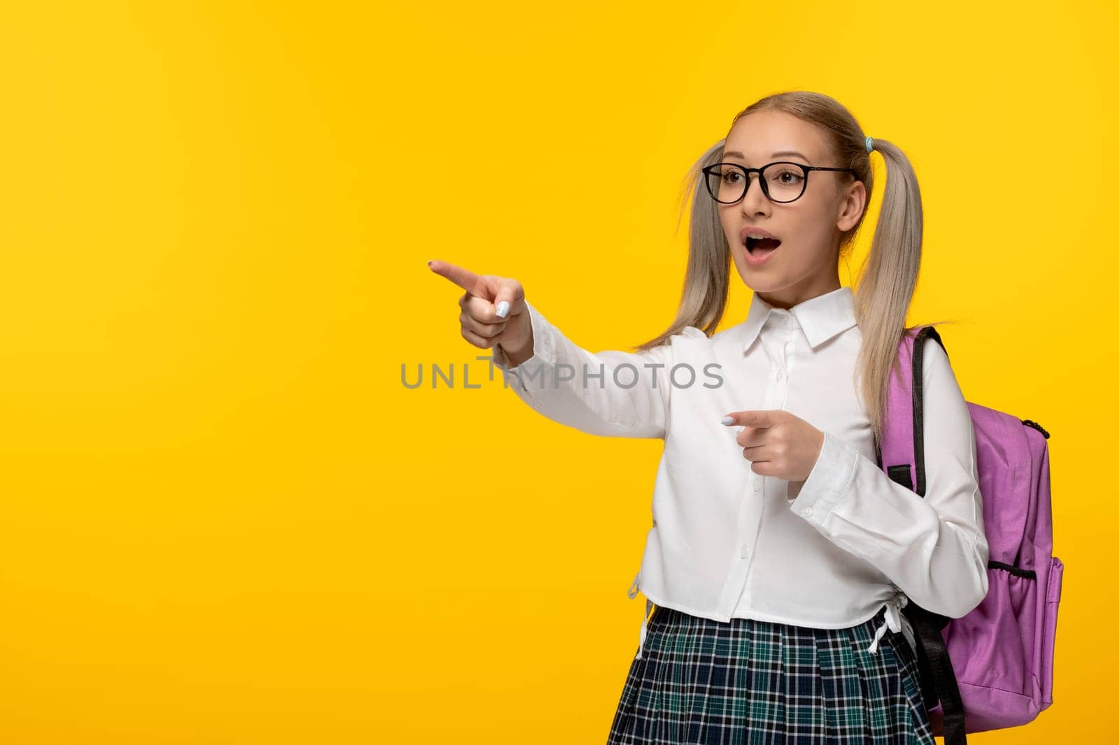 world book day blonde schoolgirl pointing front wearing glasses in uniform