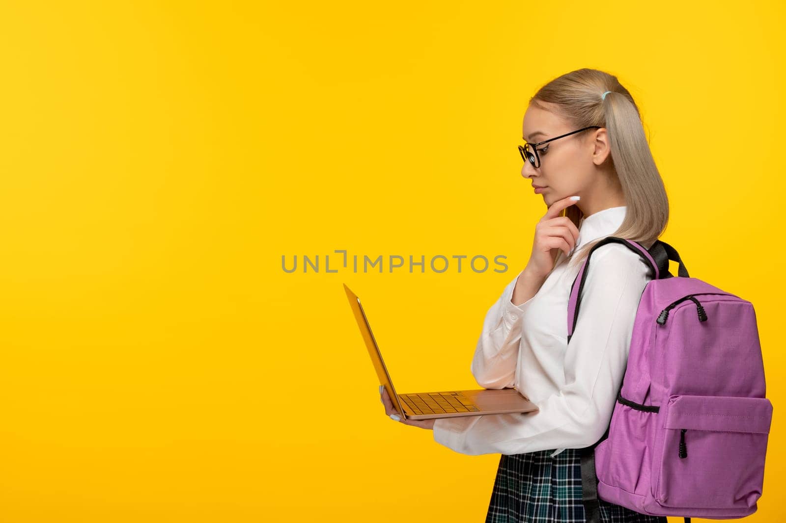 world book day blonde student with cute backpack looking at the computer screen