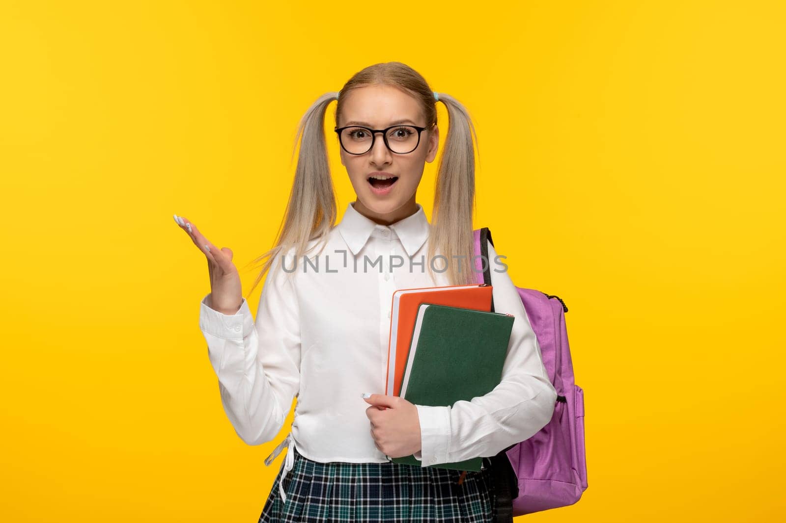 world book day cute schoolgirl holding several books on yellow background