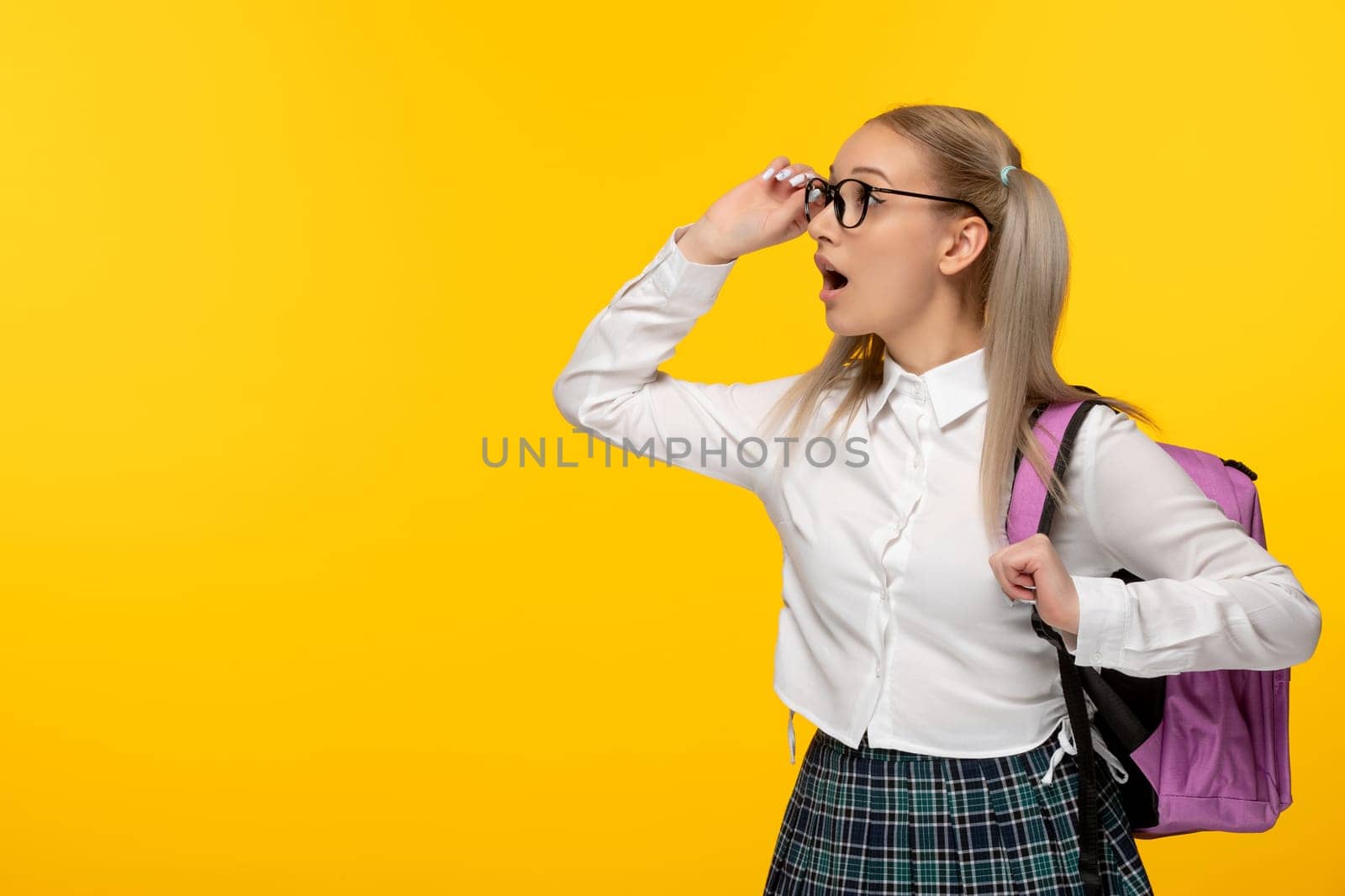 world book day cute schoolgirl looking far in glasses with pink backpack