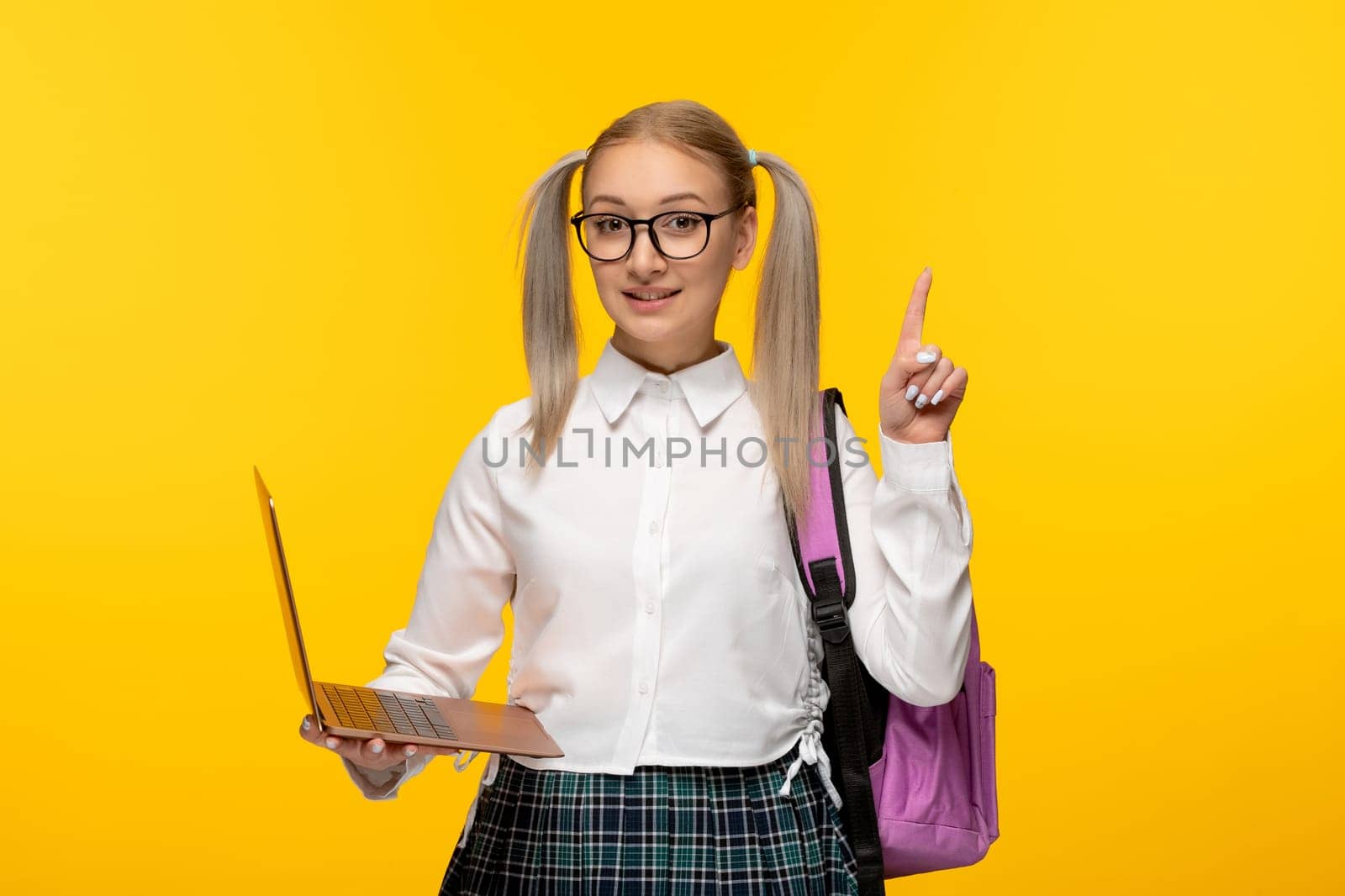 world book day excited blonde schoolgirl in uniform with pink backpack holding a computer