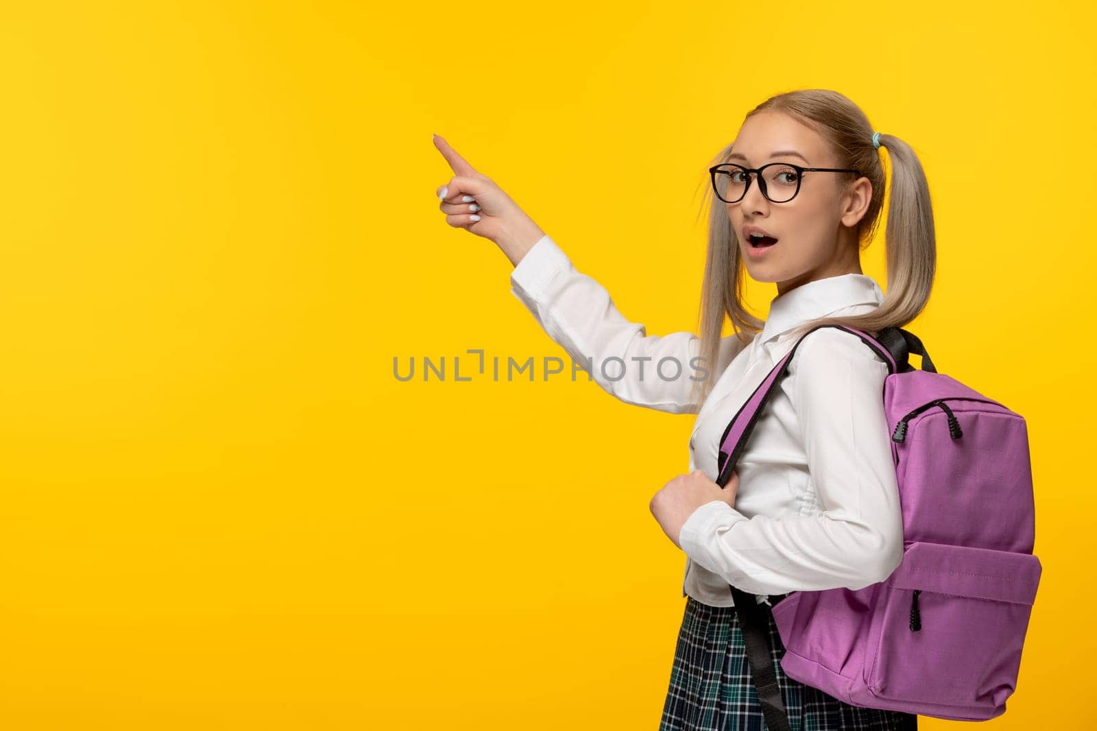 world book day excited blonde student pointing left in glasses and pink backpack by Kamran
