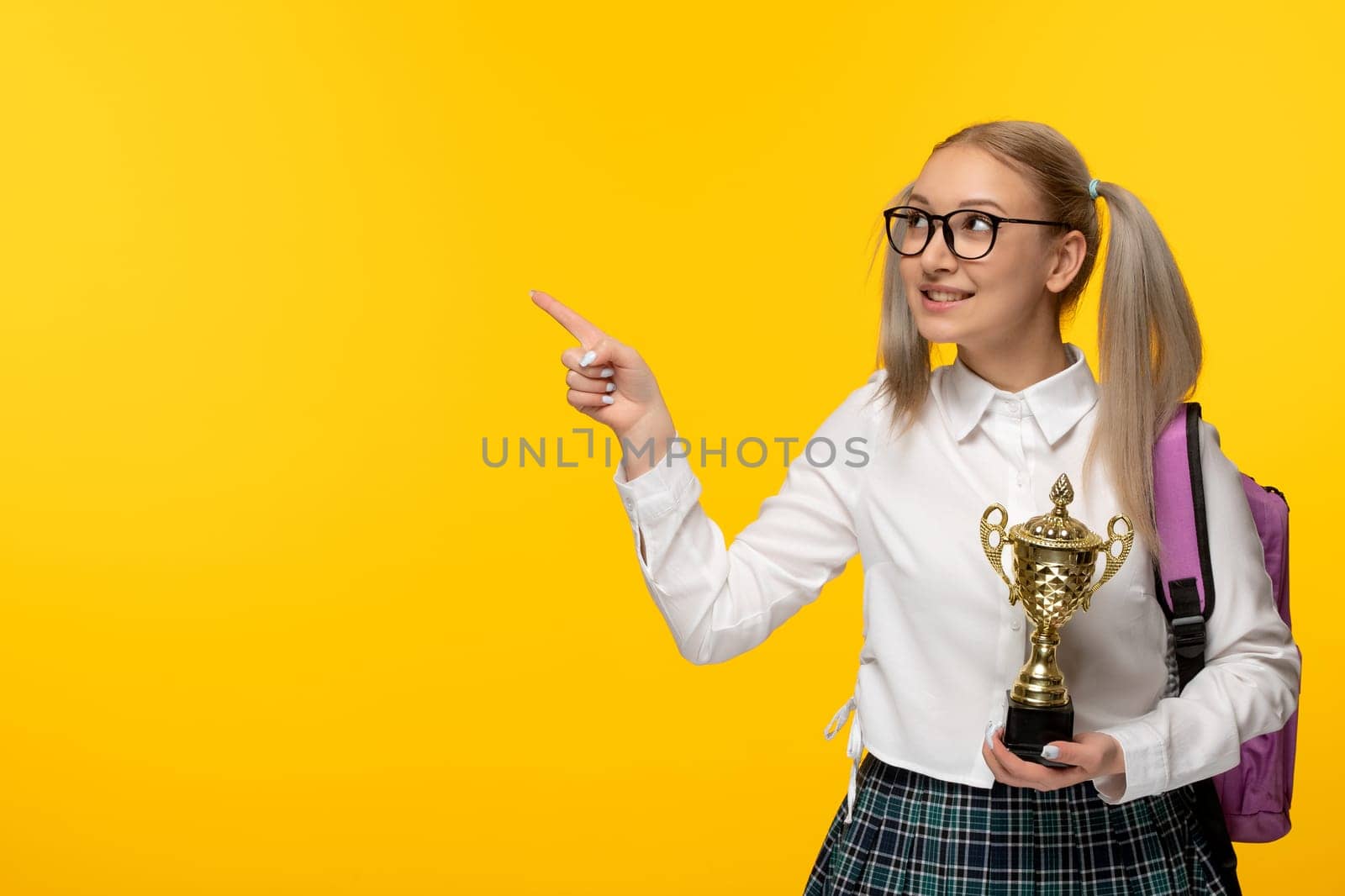 world book day excited happy school girl pointing left holding a golden trophy