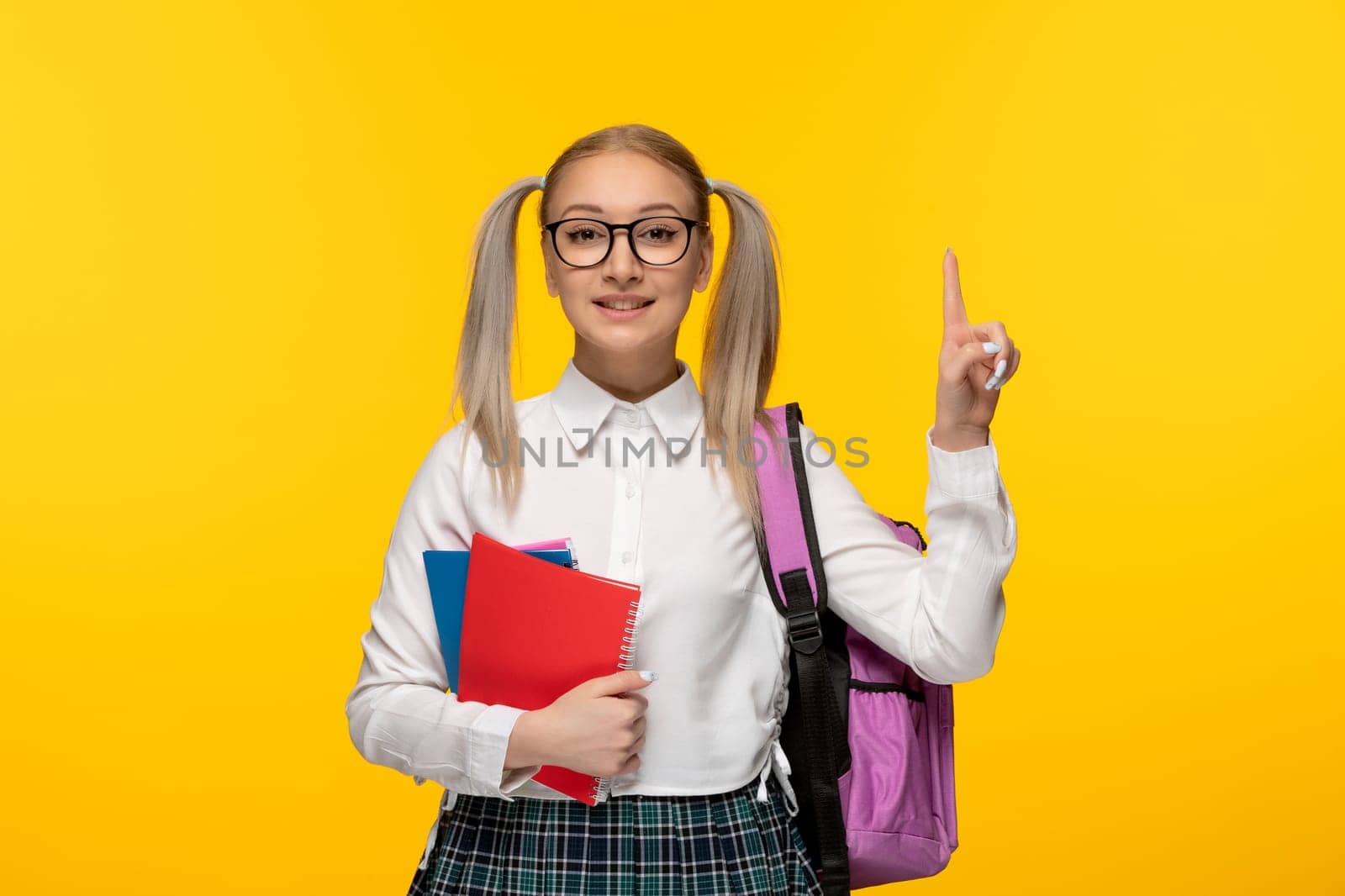 world book day excited schoolgirl pointing finger up and holding colorful notebooks