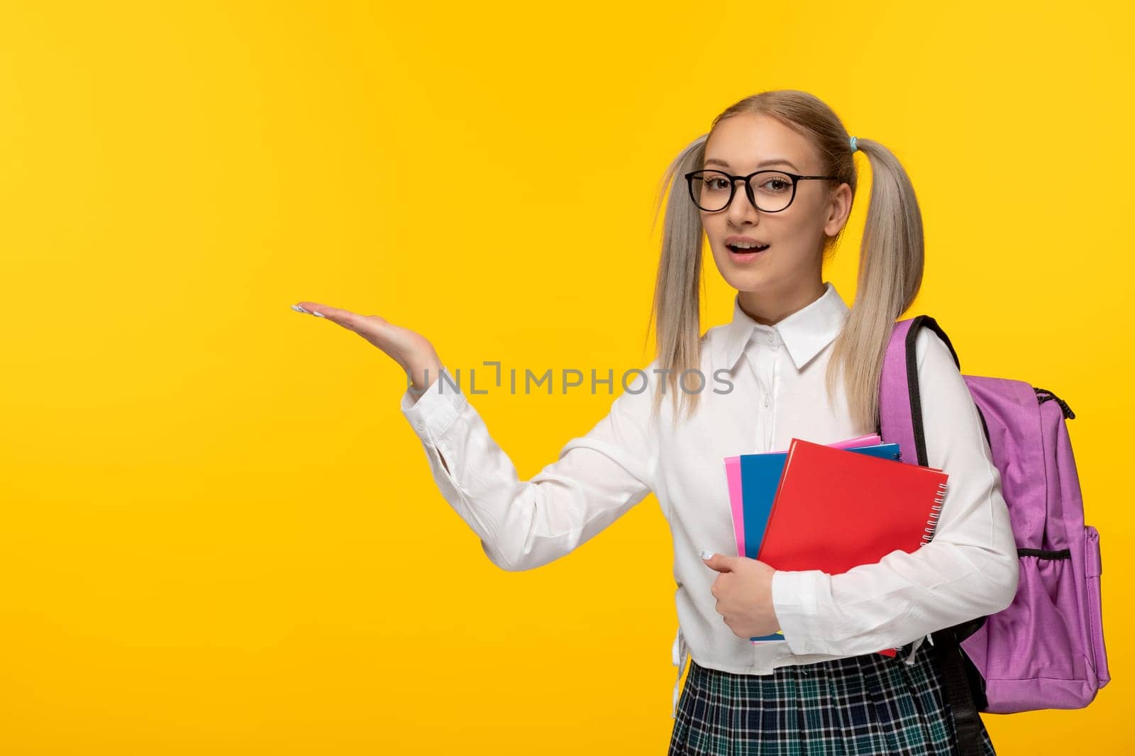 world book day happy smiling blonde schoolgirl holding books with backpack by Kamran