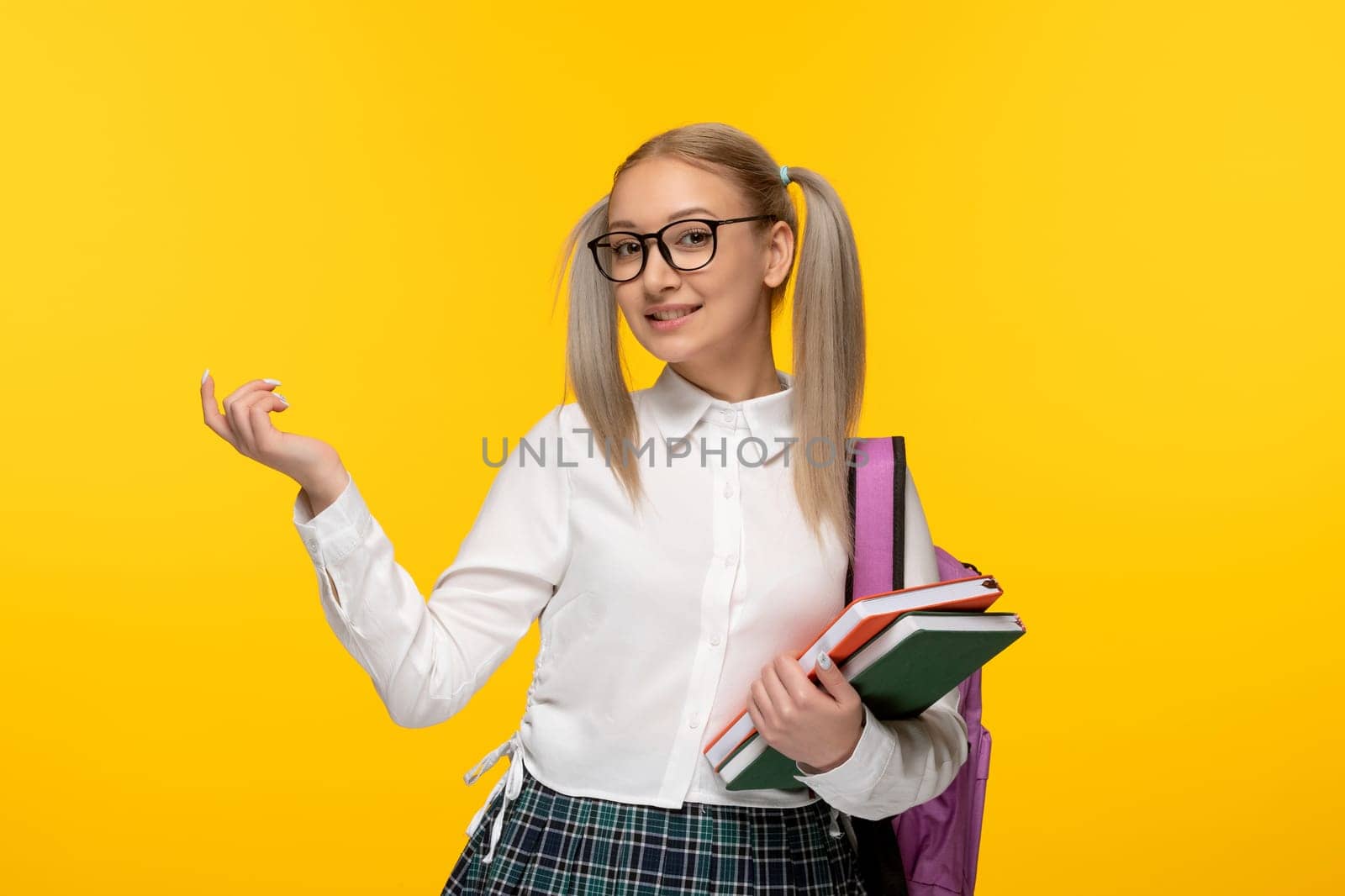 world book day smiling blonde schoolgirl holding books with backpack by Kamran