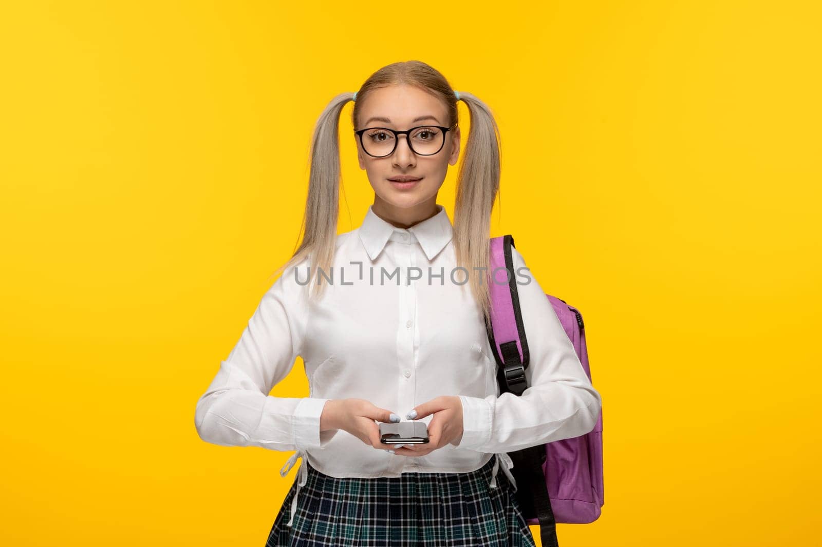 world book day smiling schoolgirl holding a phone and a pink backpack by Kamran