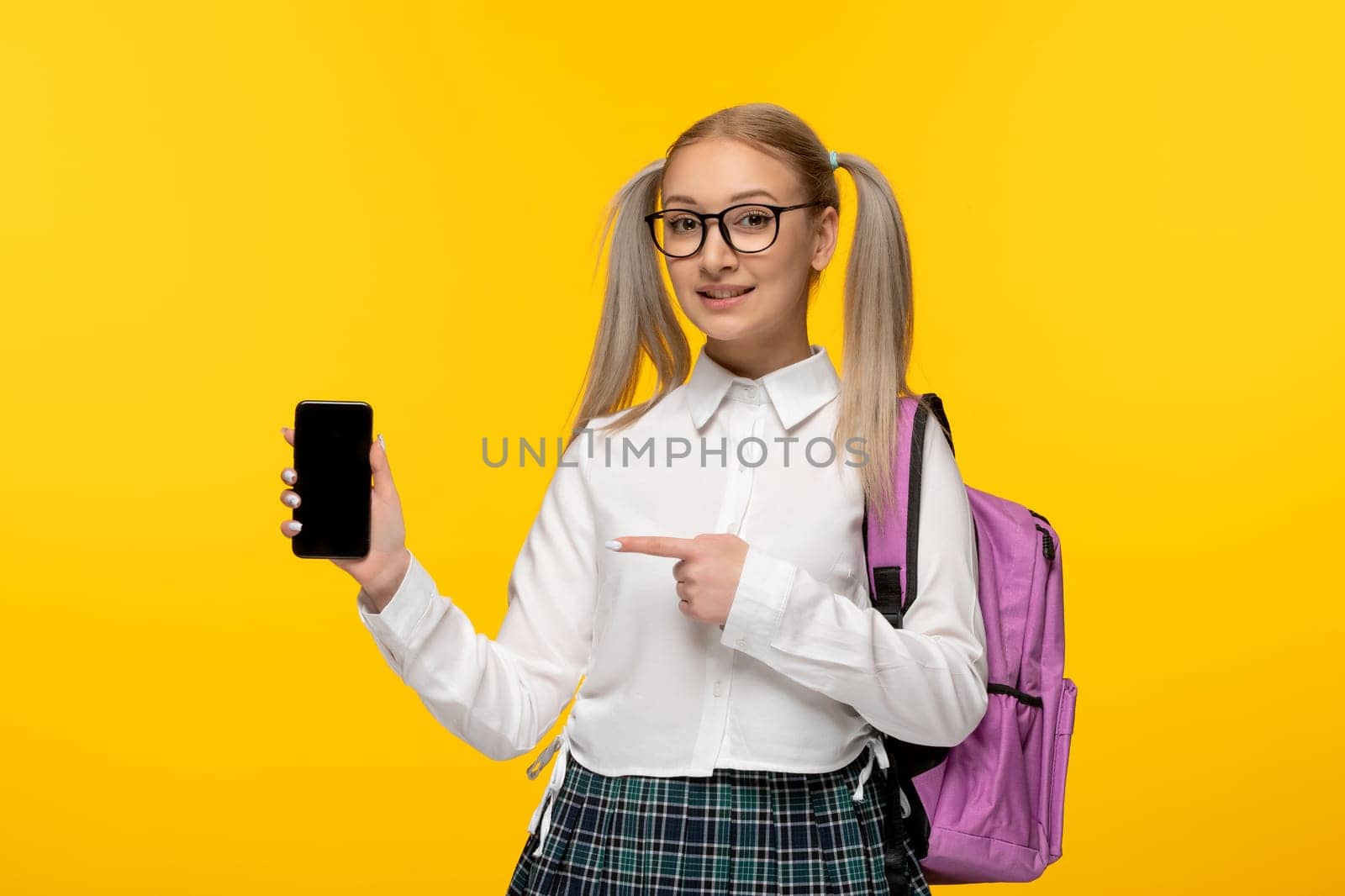 world book day smiling schoolgirl with ponytails showing a cellphone