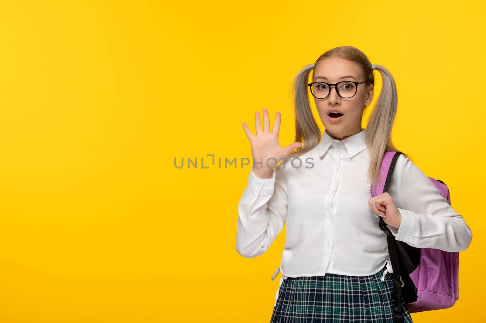 world book day surprised schoolgirl blonde with ponytails pink backpack on yellow background by Kamran