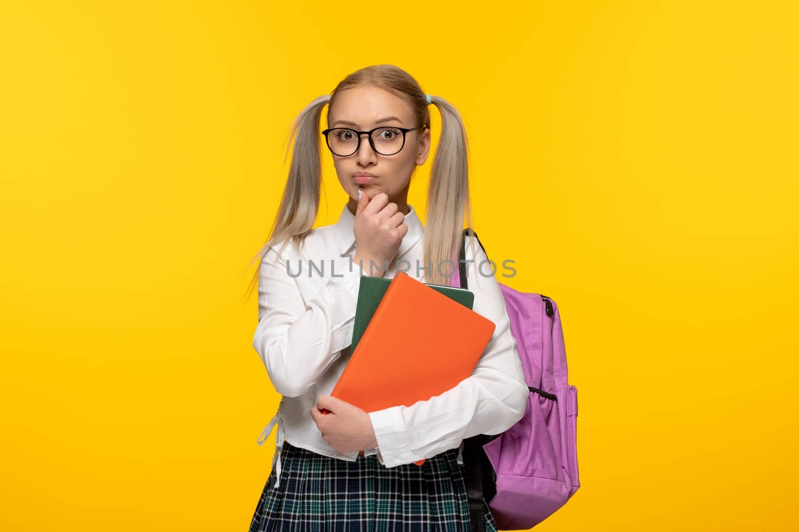 world book day thinking blonde student with ponytails holding books on yellow background