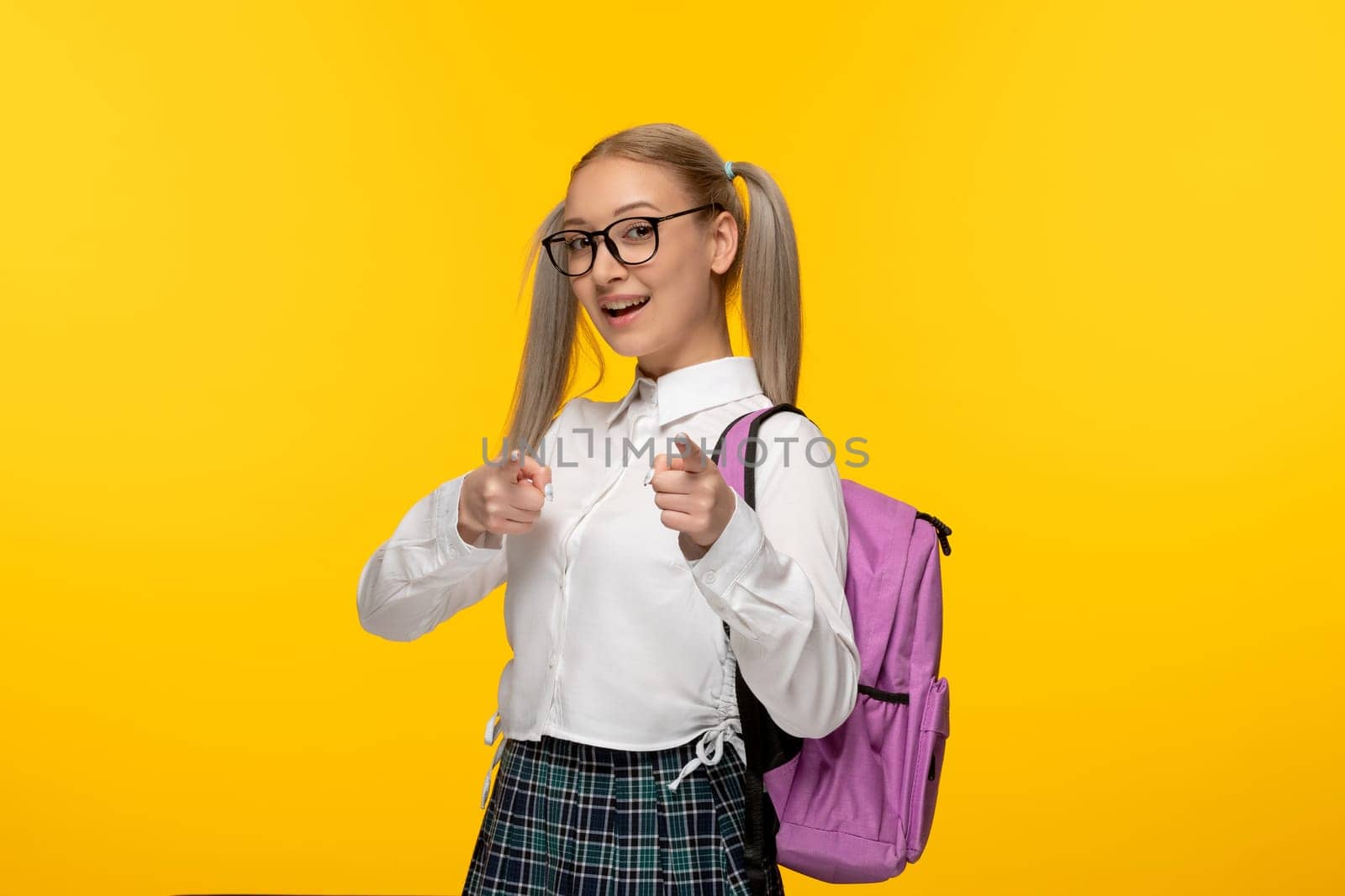 world book day young blonde schoolgirl with ponytails and pink backback showing good hand gesture