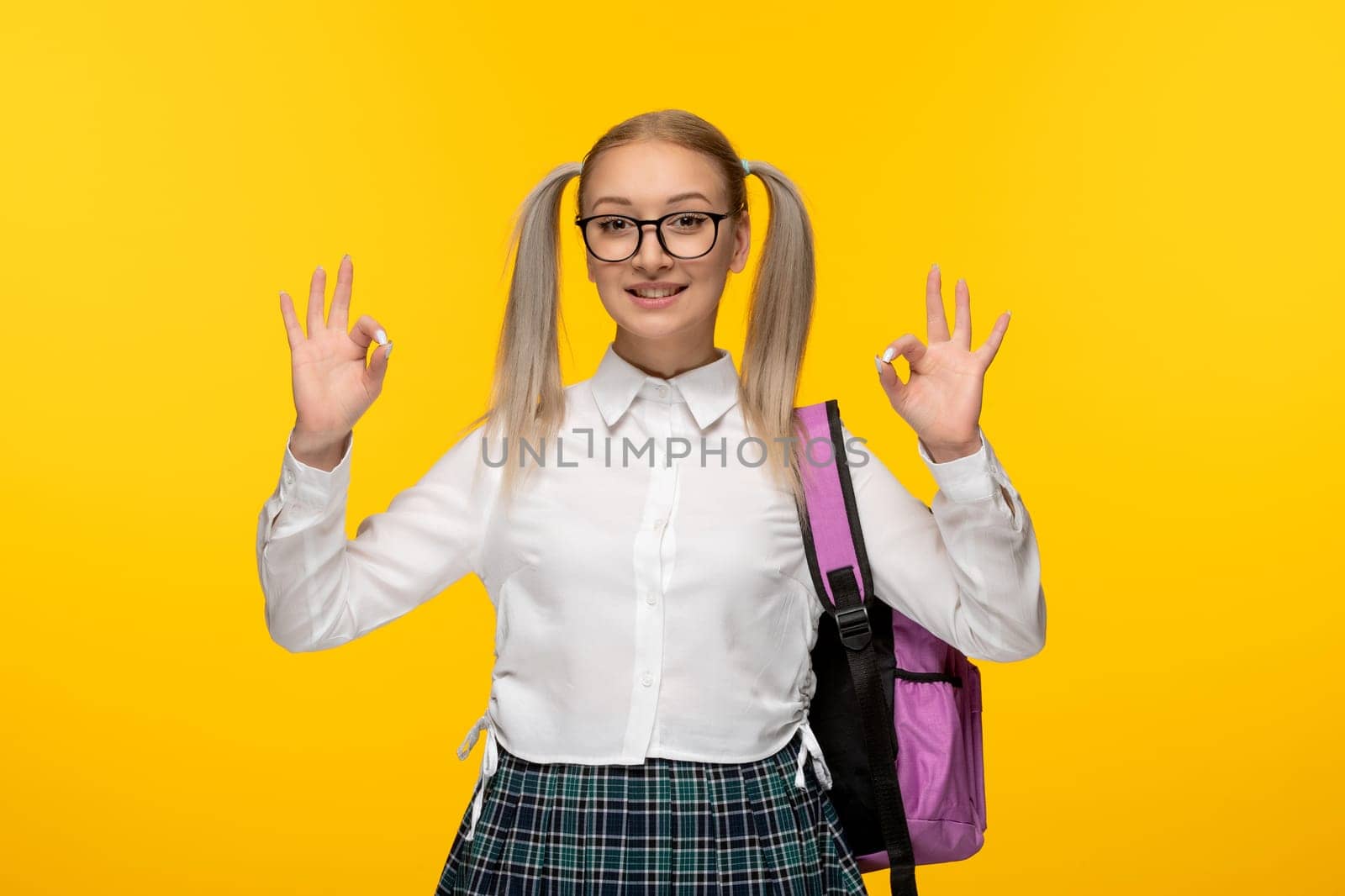 world book day young girl showing okay sign with pink backpack by Kamran