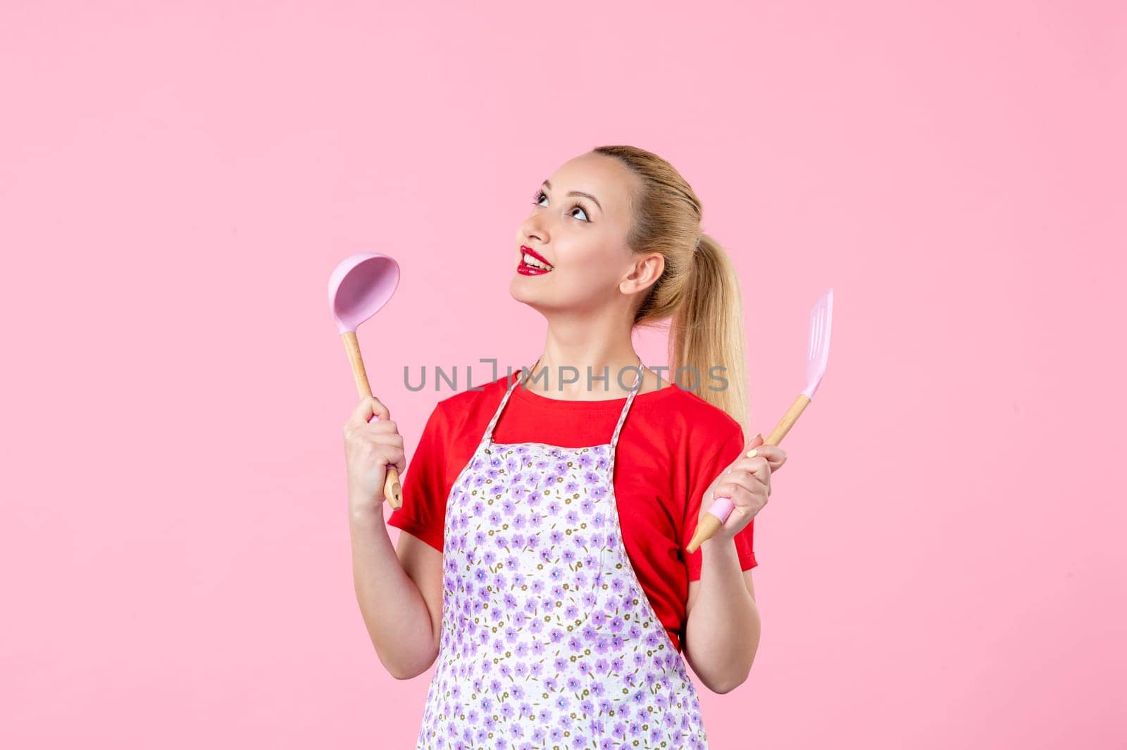 front view young pretty housewife in cape with spoons on pink background uniform job profession cooking worker wife duty horizontal occupation by Kamran