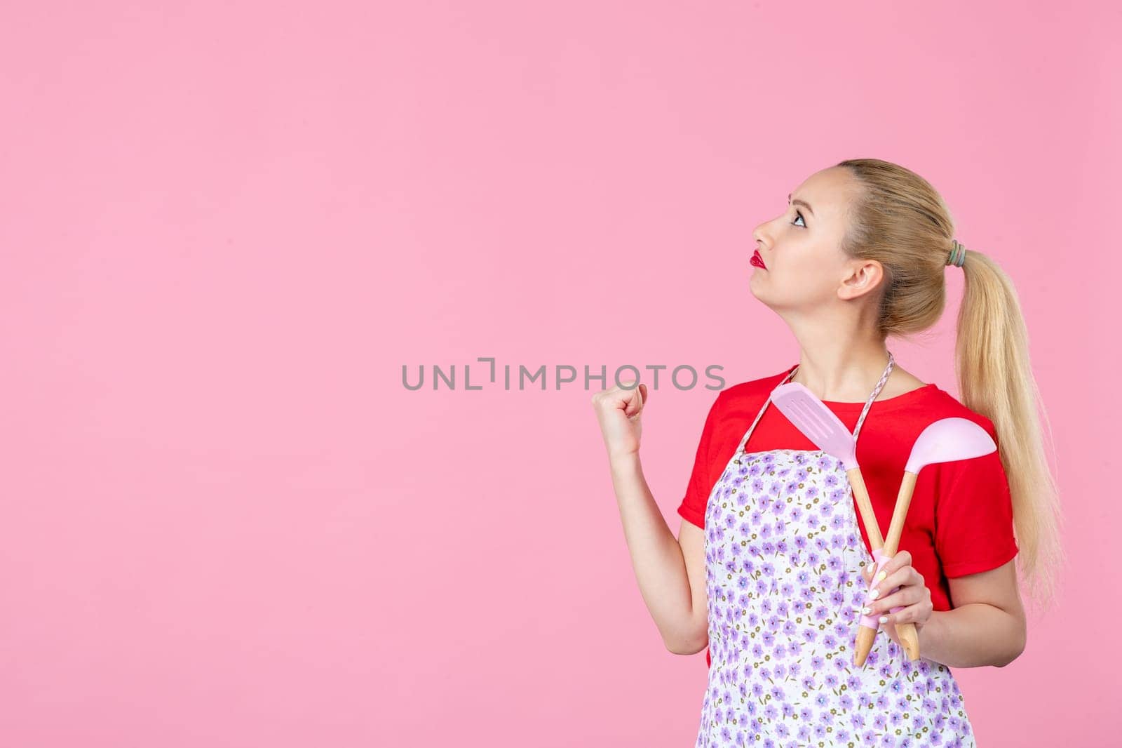 front view young housewife in cape holding spoons on pink background horizontal profession duty job worker wife cutlery occupation