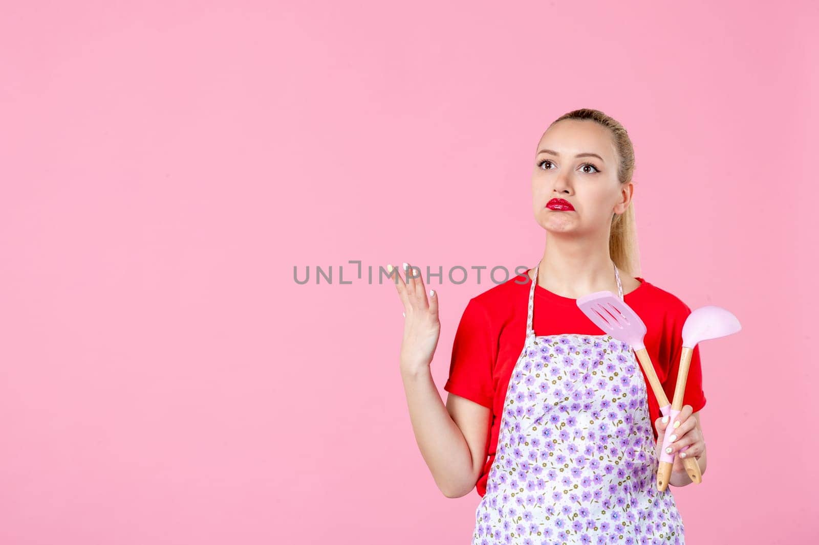front view young housewife in cape holding spoons on pink background horizontal profession occupation duty job wife uniform cutlery