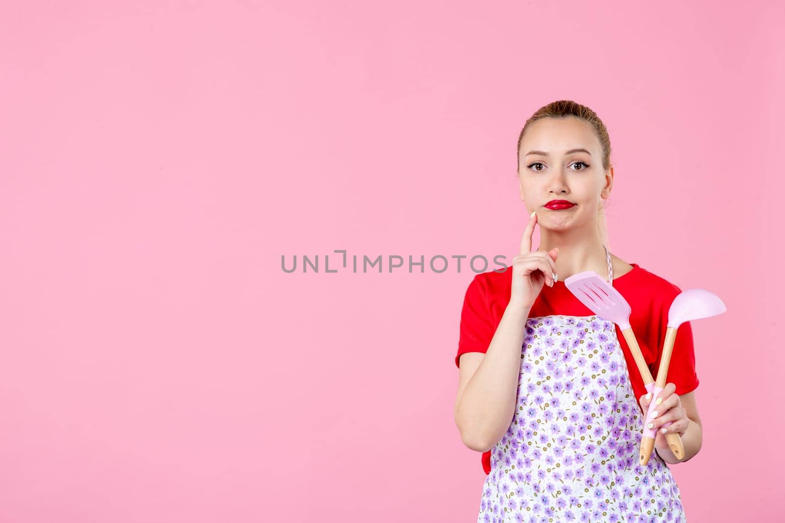 front view young housewife in cape holding spoons on pink background horizontal profession occupation duty job worker uniform cutlery by Kamran