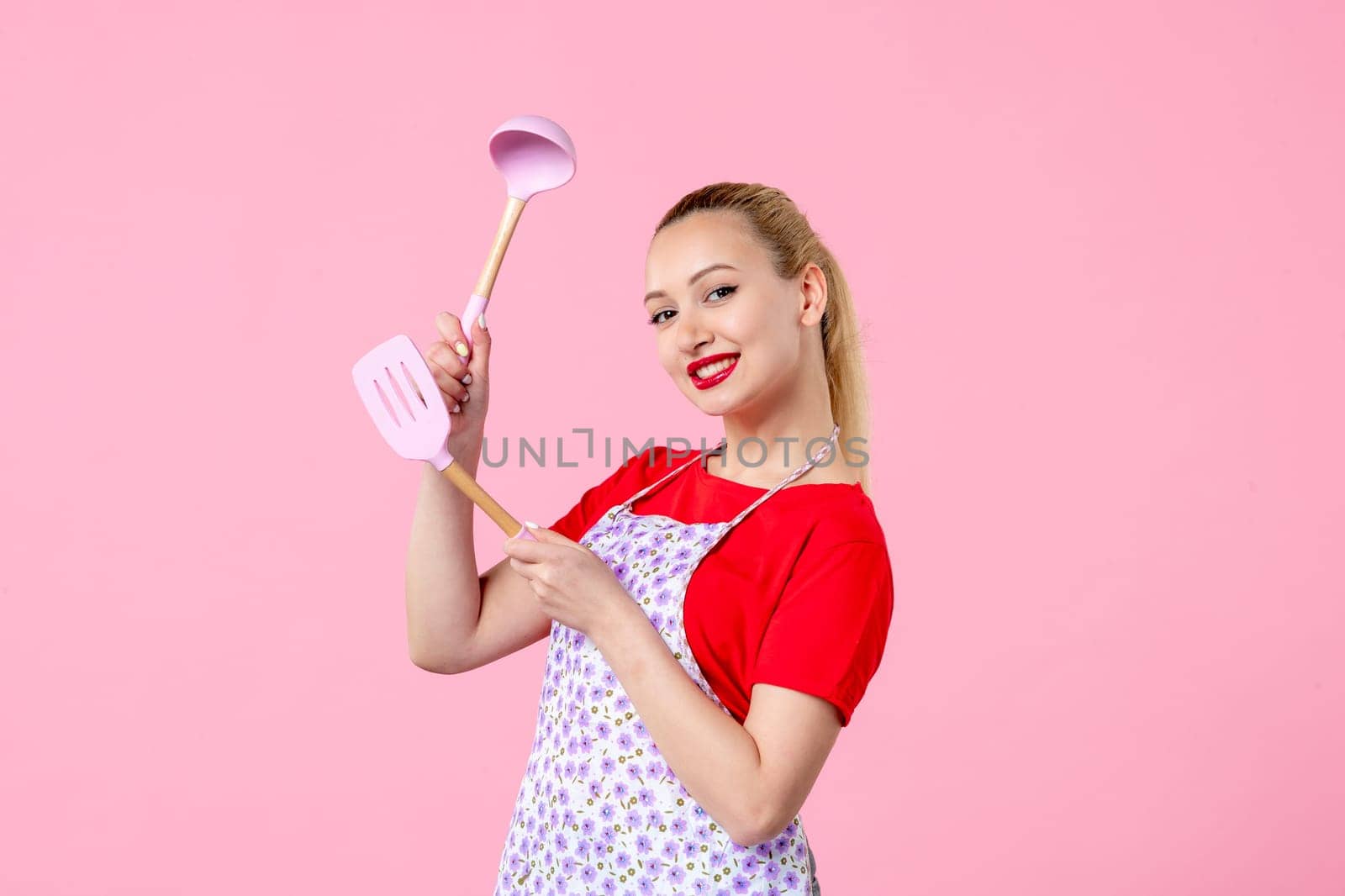 front view young housewife in cape holding spoons on pink background horizontal uniform duty occupation profession cutlery wife worker