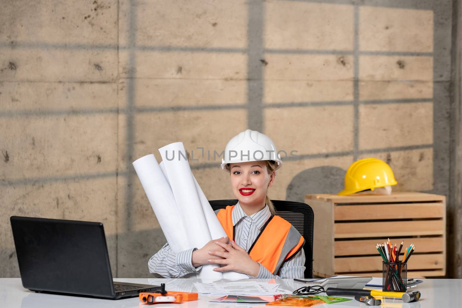 engineer blonde young cute smart girl civil worker in helmet and vest with paper rolls happy