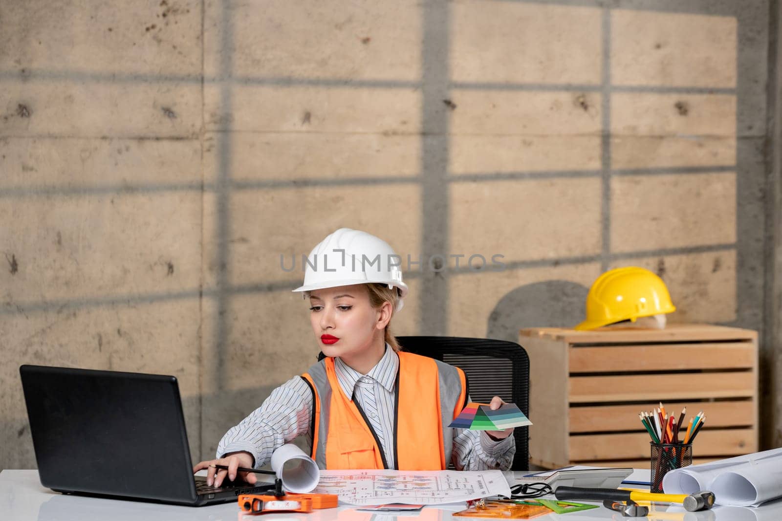 engineer blonde young cute smart girl civil worker in helmet and vest working on computer